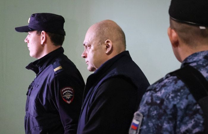 Алексей Смирнов в сопровождении сотрудников полиции — открытый кадр из судебно-процессуальной хроники.