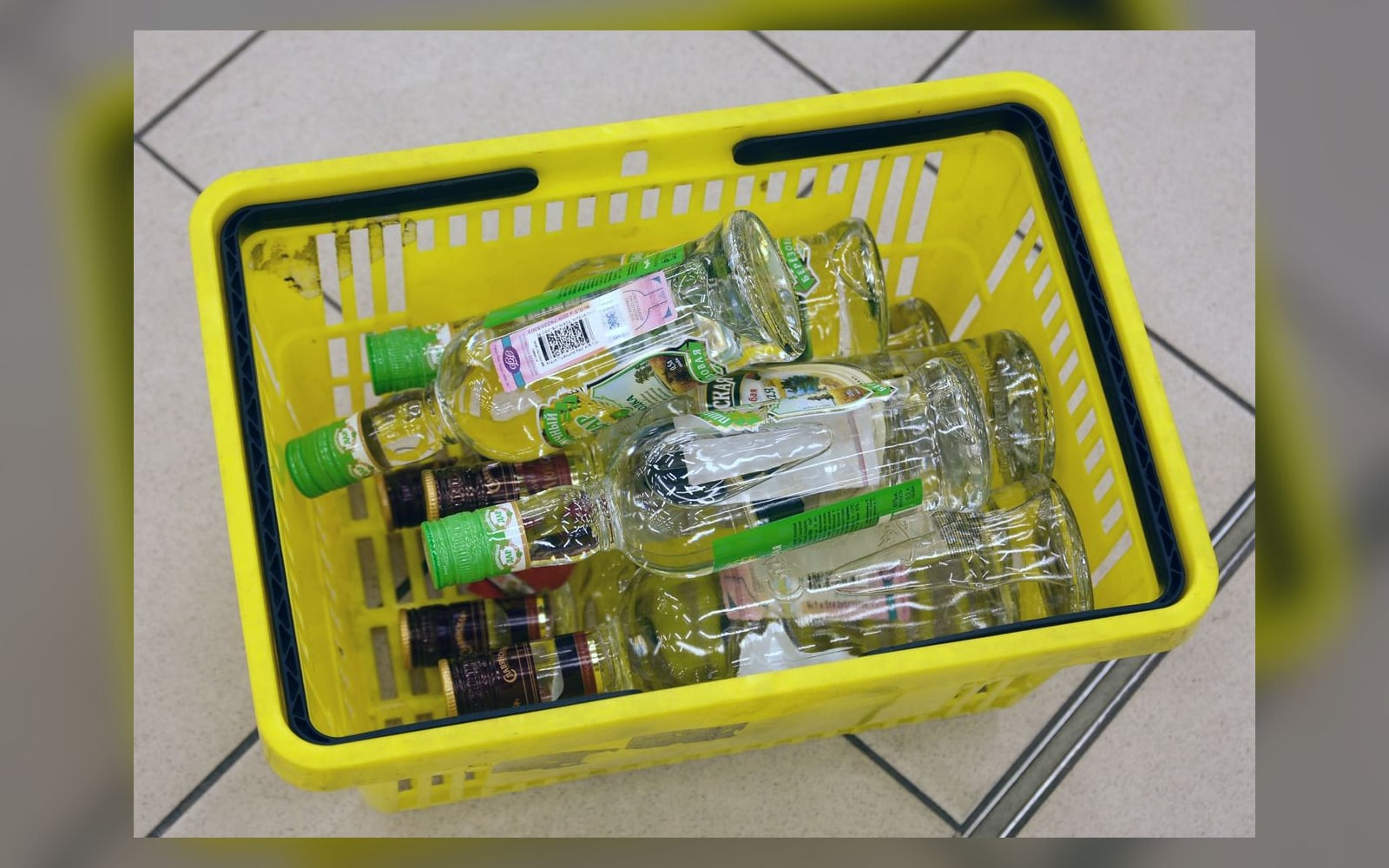 Бутылки водки с акцизными марками в магазинной корзине